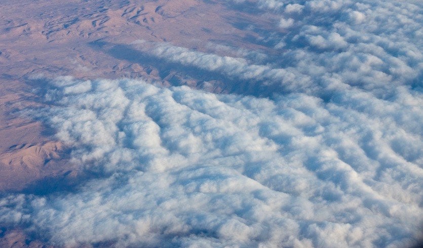 Above: Marine stratocumulus clouds from the Pacific Ocean stream atop Chile’s Atacama Desert.  Marine stratocumulus cover vast swaths of the tropical and subtropical oceans, where they reflect large amounts of sunlight and provide an overall cooling effect on climate. New global climate models are showing the potential for more global warming than long thought, perhaps due to a reduction in low-level clouds such as marine stratocumulus. Image credit: NCAR/UCAR Image and Multimedia Gallery.